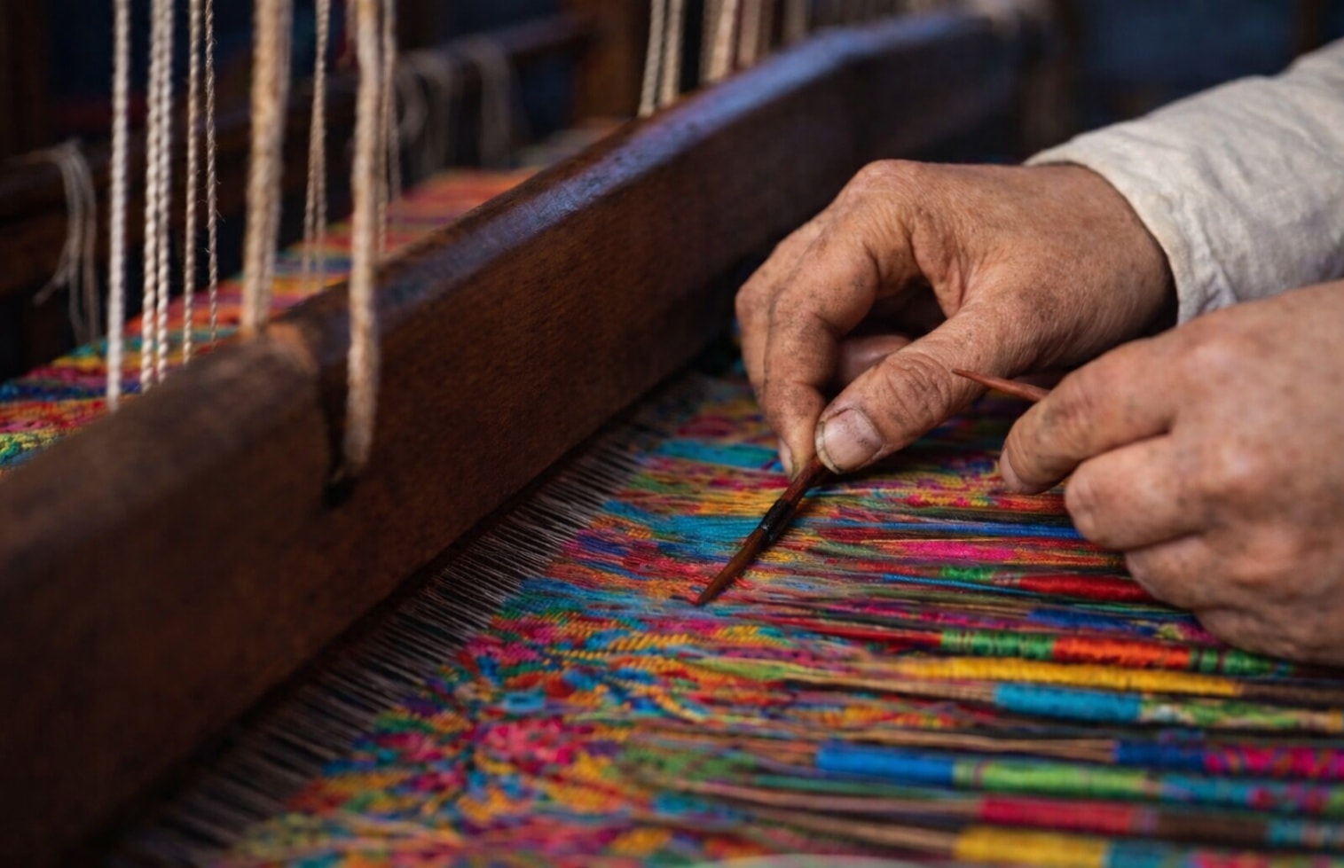 An artisan's hands weaving on a traditional Kani loom