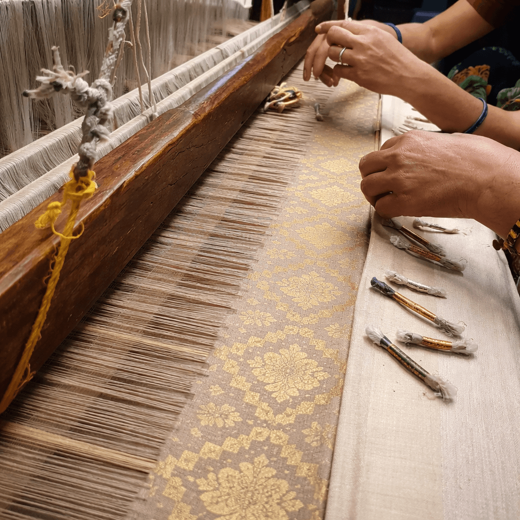 Close-up of artisan hands weaving intricate Jamdani patterns on a traditional loom
